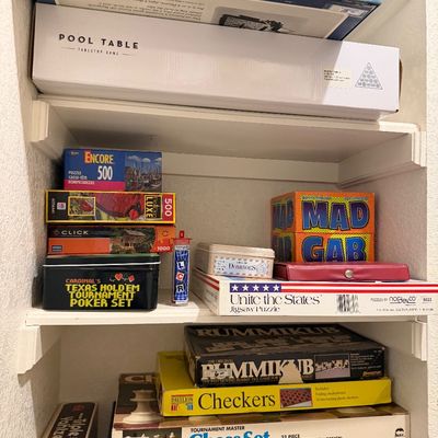 Sale Photo Thumbnail #65: Collection of boxed board games, tabletop games, and puzzles arranged on closet shelves, including Scrabble, Rummikub, Mad Gab, and a chess set.