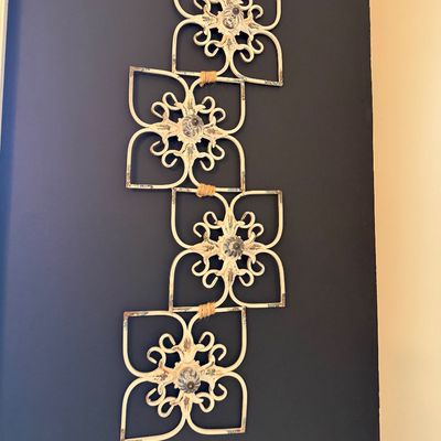 Sale Photo Thumbnail #9: Distressed cream-painted metal vertical wall art featuring four connected scrollwork flower medallions with decorative glass center knobs.