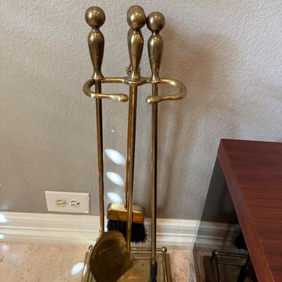 Sale Photo Thumbnail #84: Vintage brass fireplace tool set with stand, including a poker, shovel, broom, and tongs, featuring polished ball handles.