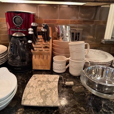Sale Photo Thumbnail #48: Kitchen counter assortment featuring a red Mr. Coffee maker, Wüsthof knife block, ceramic dishware, a marble cheese slicer, and stainless steel mixing bowls.
