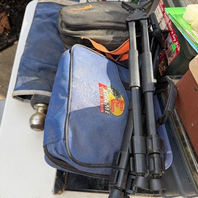 Sale Photo Thumbnail #98: Assortment of outdoor gear, including a blue Bass Pro Shops worm binder bag, a black shooting rest tripod, and a trailer hitch ball mount.