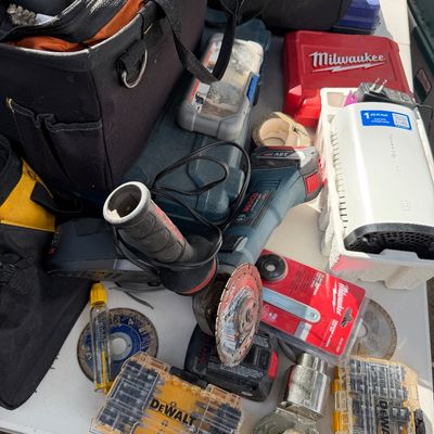 Sale Photo Thumbnail #100: Assortment of power tools and accessories, including a Bosch 18V angle grinder, DeWalt bit sets, tool bags, and a Milwaukee case.