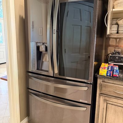 Sale Photo Thumbnail #8: Modern LG InstaView French door refrigerator in a black stainless steel finish with exterior water dispenser and pull-out freezer drawers.