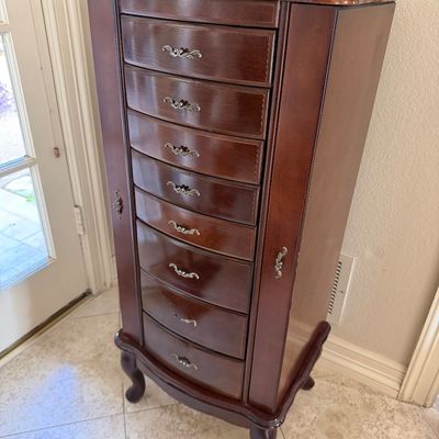 Sale Photo Thumbnail #19: Traditional dark wood standing jewelry armoire featuring eight drawers, side door compartments, and ornate metal pulls on cabriole legs.