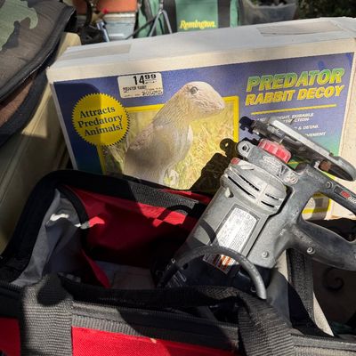 Sale Photo Thumbnail #101: Handheld power saw sitting in a fabric tool bag next to a vintage Predator Rabbit Decoy box and assorted outdoor gear.