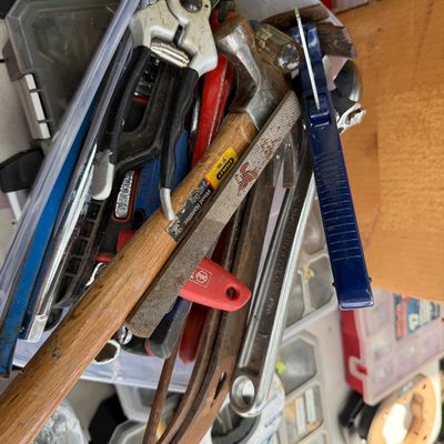 Sale Photo Thumbnail #90: Assorted hand tools gathered in a clear plastic bin, including a wood-handled Stanley hammer, pruning shears, files, and wrenches.