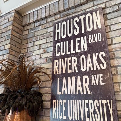 Sale Photo Thumbnail #41: Large subway scroll-style Houston wall sign resting on a brick fireplace mantel next to a decorative feather arrangement.