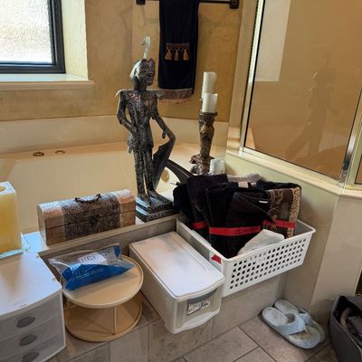 Sale Photo Thumbnail #33: Bathroom decor and organization items, including a metal knight statue, a decorative box, pillar candles, plastic storage drawers, and bath towels arranged near a bathtub.