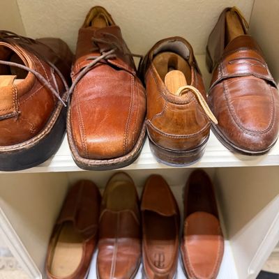 Sale Photo Thumbnail #27: Selection of men's brown leather dress shoes and loafers arranged on closet shelving, featuring wooden shoe trees in several pairs.