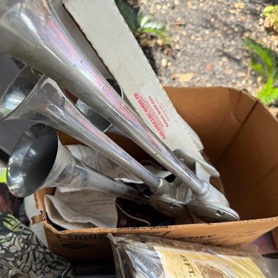 Sale Photo Thumbnail #86: Set of three vintage chrome air horns stored in a cardboard box, displaying light surface wear.