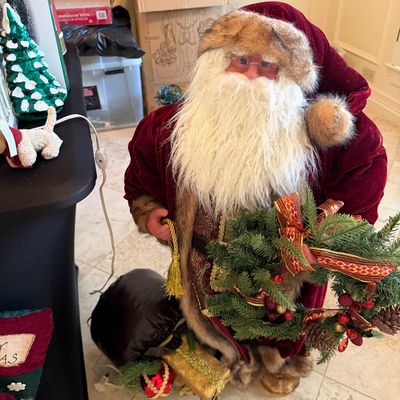 Sale Photo Thumbnail #10: Standing Father Christmas figure in a faux-fur-trimmed velvet suit, holding a holiday wreath and toy sack.