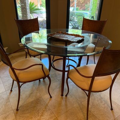 Sale Photo Thumbnail #43: Round glass-top dining table with a metal frame and four matching armchairs featuring upholstered seats and high curved backs.