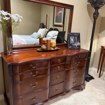Sale Photo Thumbnail #56: Traditional serpentine-front mahogany triple dresser with matching framed mirror and metal bail handles.