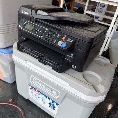 Sale Photo Thumbnail #69: Black Epson WorkForce WF-2650 all-in-one printer sitting atop a light gray Coleman 316 Series cooler.