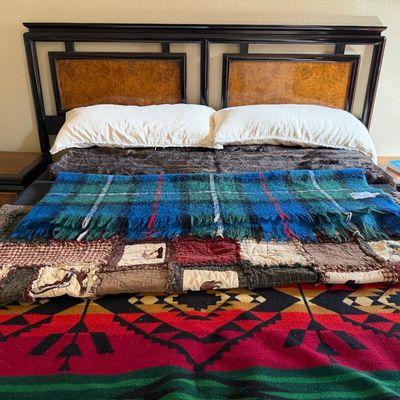 Sale Photo Thumbnail #15: Asian-inspired dark wood and burl veneer king bed frame with matching nightstands, layered with blankets including a vibrant geometric Pendleton-style throw and a mohair tartan plaid blanket.