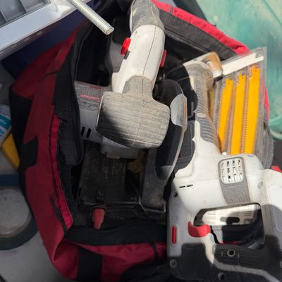 Sale Photo Thumbnail #92: Red canvas tool bag containing various power tools including a cordless reciprocating saw and circular saw, showing signs of heavy use.