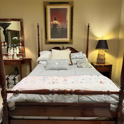 Sale Photo Thumbnail #51: Traditional dark wood four-poster bed frame dressed in light grey linens with decorative throw pillows and a patch quilt.