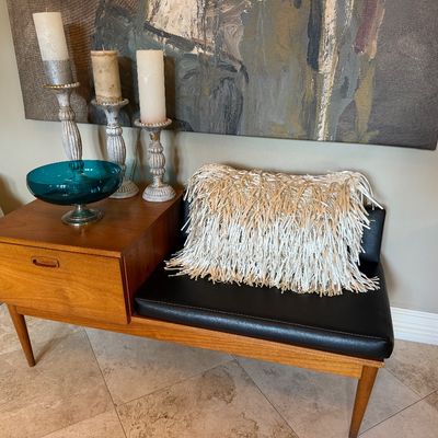 Sale Photo Thumbnail #2: Mid-century modern teak telephone bench with a single drawer and black vinyl seat cushion, styled with a teal glass bowl and decorative candlesticks.
