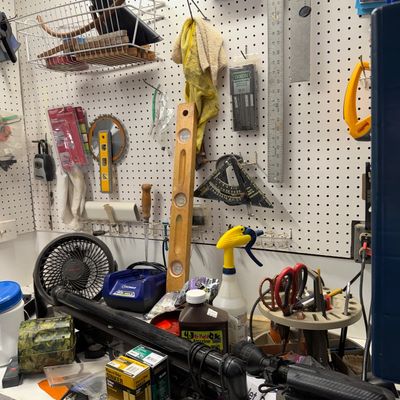 Sale Photo Thumbnail #107: Workshop workbench area cluttered with assorted hand tools, power tool accessories, hardware supplies, and pegboard storage items.