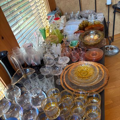 Sale Photo Thumbnail #71: Large collection of vintage glassware displayed on a table, including gold-rimmed lowballs, cobalt blue goblets, pink depression glass, and marigold carnival glass pieces.