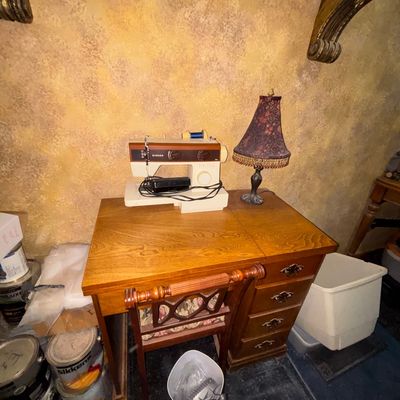 Sale Photo Thumbnail #30: Vintage Singer sewing machine sitting atop a wooden sewing desk with matching chair and small accent lamp.