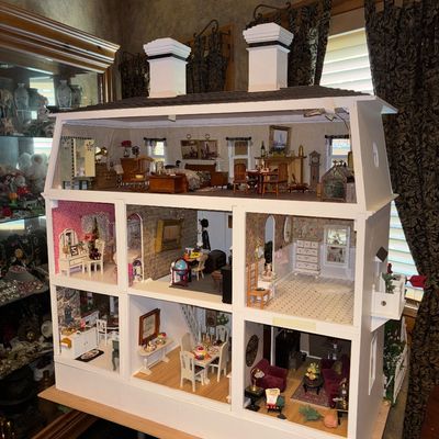Sale Photo Thumbnail #32: Large multi-story wooden dollhouse with white exterior, dual chimneys, and fully furnished rooms featuring detailed miniature decor.