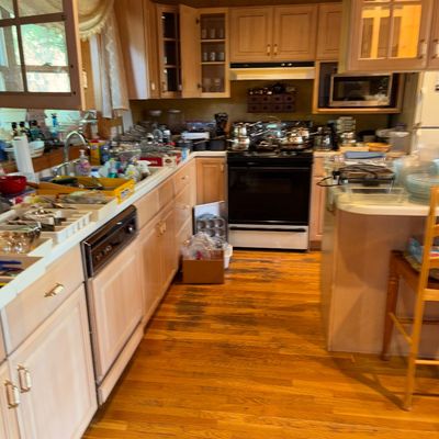 Sale Photo Thumbnail #81: Kitchen filled with a wide assortment of household cookware, glassware, small appliances, and organizer trays laid out on the light wood cabinets and countertops.