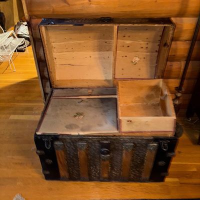Sale Photo Thumbnail #125: Antique dome-top steamer trunk with wood slats, embossed metal banding, and original interior compartment tray with floral decal details.