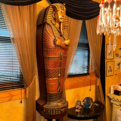 Sale Photo Thumbnail #108: Large Egyptian revival Tutankhamun sarcophagus display cabinet, featuring painted details and gilt accents.