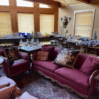 Sale Photo Thumbnail #16: French Provincial style sofa with carved wooden frame and burgundy upholstery, accompanied by a matching armchair and floral tapestry accent pillows.