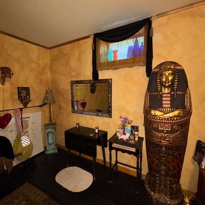 Sale Photo Thumbnail #119: Large Egyptian pharaoh sarcophagus cabinet or statue, displayed alongside small accent tables, a mosaic mirror, and various decorative items.