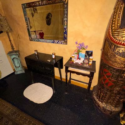 Sale Photo Thumbnail #115: Eclectic hallway scene featuring a large Egyptian sarcophagus replica, a mosaic-framed wall mirror, and two dark wooden accent tables with various knickknacks.