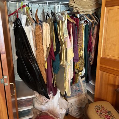 Sale Photo Thumbnail #64: Closet packed with vintage textiles, garments, and fabrics, alongside storage bins and an upholstered footstool with floral embroidery.