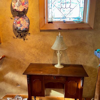 Sale Photo Thumbnail #35: Vintage dark wood writing desk with a textured table lamp, accompanied by a three-tiered decorative plate wall rack and leaded glass window.