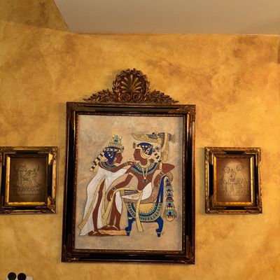Sale Photo Thumbnail #109: Framed Egyptian papyrus painting depicting a pharaoh and queen, flanked by two smaller framed Egyptian art prints in matching ornate gold frames.