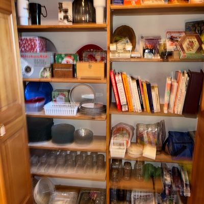 Sale Photo Thumbnail #80: Pantry cabinet filled with various household items, including glassware, serving dishes, kitchen gadgets, cookbooks, and storage containers.