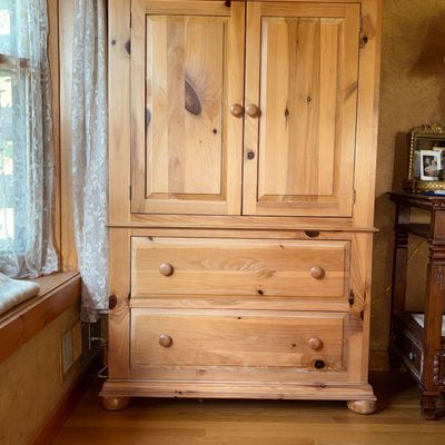 Sale Photo Thumbnail #49: Rustic knotty pine armoire featuring a top cabinet with two panel doors over two wide drawers with wood knobs.