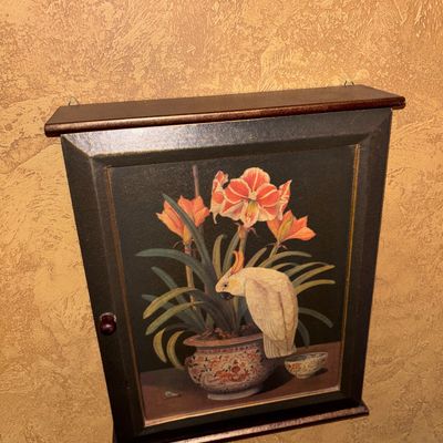 Sale Photo Thumbnail #82: Wall-mounted dark wooden cabinet featuring a botanical and cockatoo art print on the front door.