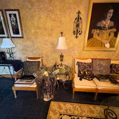 Sale Photo Thumbnail #87: Living room setup featuring a wooden armchair and sofa with upholstered cushions, flanked by glass-top tables, decorative lamps, and framed wall art.