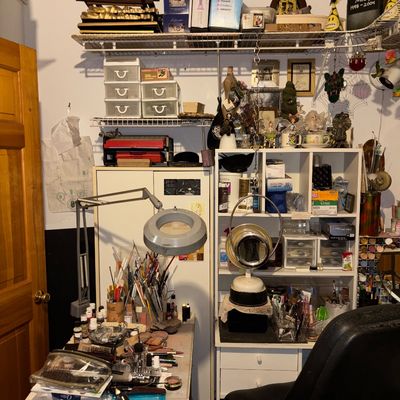 Sale Photo Thumbnail #107: Craft studio setup featuring desks, a magnifying desk lamp, various art supplies, storage drawers, and wall shelving.