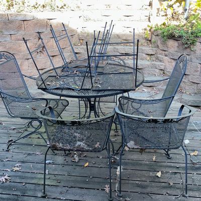 Sale Photo Thumbnail #58: Black wrought iron outdoor patio set featuring a round mesh-top table and matching armchairs.