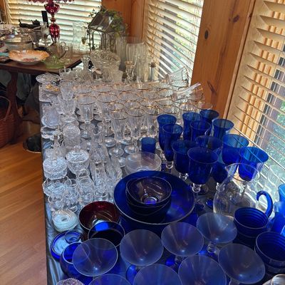 Sale Photo Thumbnail #68: Large collection of glassware featuring cobalt blue stems and bowls, gold-rimmed crystal goblets, and pressed cut glass serving pieces.