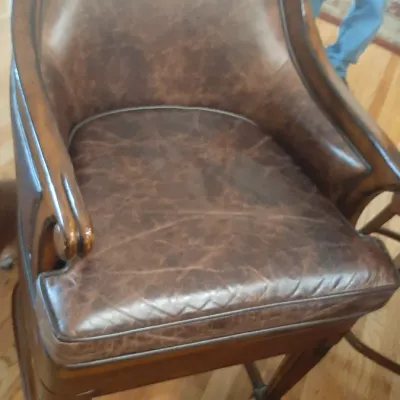 Traditional style high-backed leather bar stool with a rich brown wood frame, padded seat, and metal footrest.
