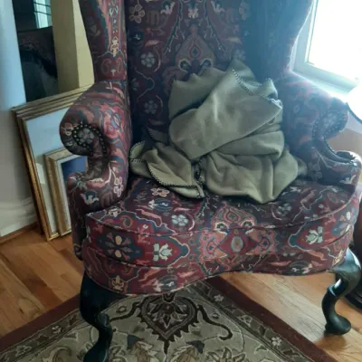 Traditional wingback armchair with patterned tapestry upholstery, nailhead trim, and dark cabriole legs.