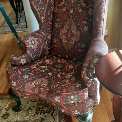 Traditional wingback armchair upholstered in a multi-colored tapestry pattern with cabriole legs and nailhead trim.