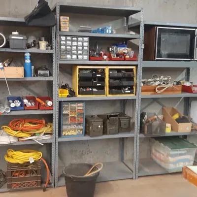 Heavy-duty metal workshop shelving units organized with various hardware, small parts storage bins, extension cords, and a vintage...