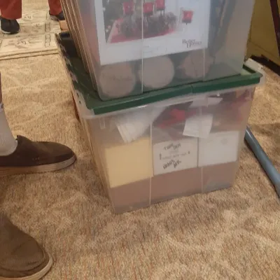 Two stacked clear plastic storage totes with green lids containing various home decor and household items.