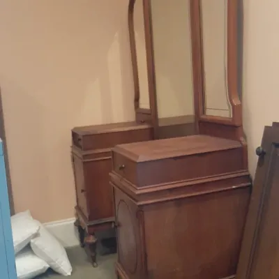 Antique wooden vanity dresser featuring a tri-fold mirror, two side pedestals with cabinet drawers, and turned legs.
