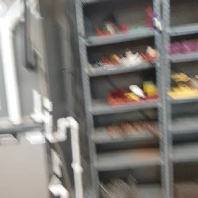 Grey metal industrial shelving units holding various household tools and supplies in a basement workshop area.