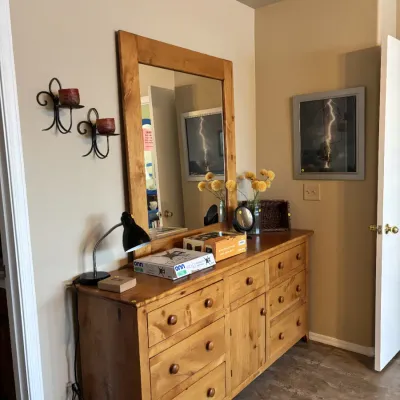 Sale Photo Thumbnail #17: Rustic pine long dresser with a matching wall mirror, paired with a small desk lamp and assorted home decor.